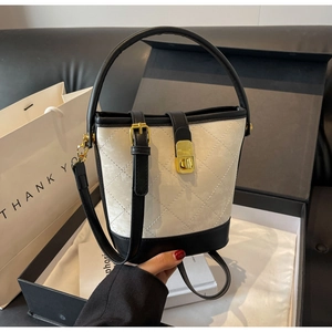 Detail of quilted bucket bag with gold clasp and elegant black and white color contrast