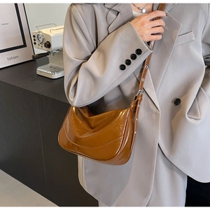 Detail of caramel glossy faux leather half-moon bag with adjustable metal buckle strap