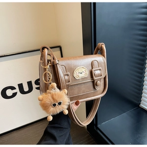 Gros plan du sac carré en cuir PU marron avec broderie chiot et pendentif peluche