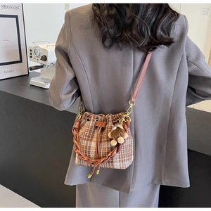 Détail du sac seau à carreaux en laine avec bandoulière cuir et breloque ourson