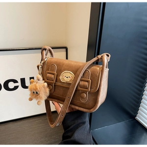 Gros plan sur un sac à bandoulière marron rétro avec broderie et breloque pompon mignon