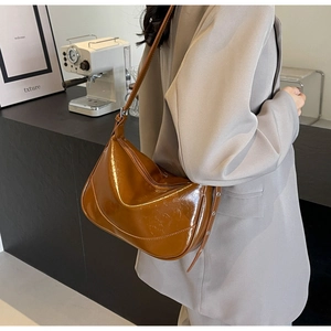 Brown patent leather underarm bag with vintage texture shown in a minimalist room