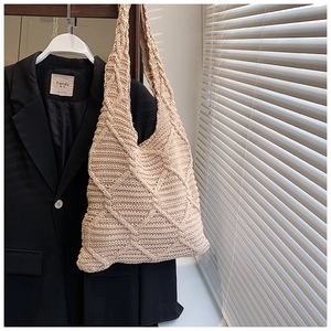 Dettaglio della borsa tote in maglia beige con motivo a rombi e tracolla stile hobo
