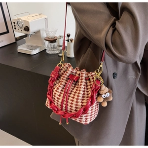 Détail du sac seau en tweed pied-de-poule rouge avec bandoulière et pendentif peluche