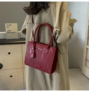 Détail du sac à main rouge foncé avec texture écorce verticale et pendentif en cœur