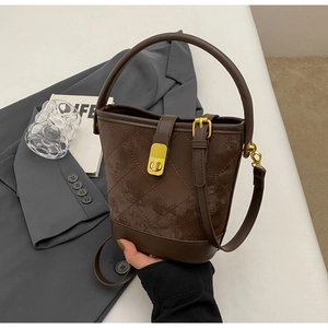 Detailed view of brown quilted bucket bag featuring a gold twist lock and top handle