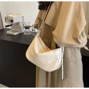 Detail of a creamy white half-moon hobo bag in polished PU leather with adjustable strap