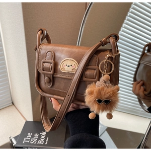 Détail du sac bandoulière marron foncé avec broderie chiot et pendentif en peluche