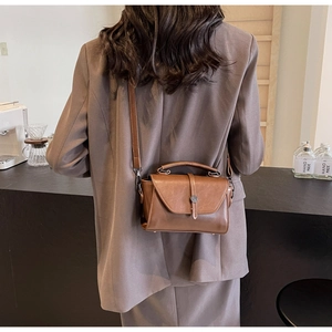 Brown retro crossbody bag worn by model, showcasing side view in cozy cafe setting