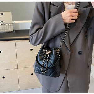 Close-up of quilted leather bucket bag with gold-tone chain strap and drawstring closure