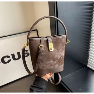 Detail of a brown bucket bag featuring quilted stitching and golden metal clasp closure