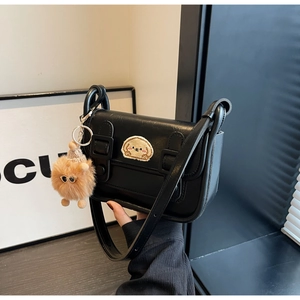 Détail du petit sac noir carré avec écusson chien mignon et pompon en peluche décoratif