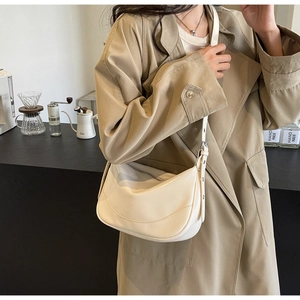 Detail of a creamy white crescent hobo bag made of soft leather on a model's shoulder