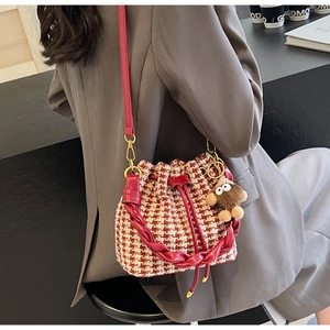 Détail du sac seau à motif pied-de-poule rouge avec cordon en cuir et breloque singe