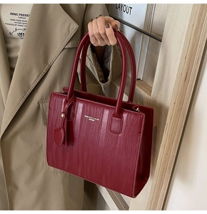 Détail du sac cabas bordeaux avec texture ondulée et pendentif en forme de cœur