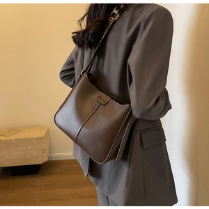 Detail of dark brown bucket bag with leopard print wide strap and gold buckle