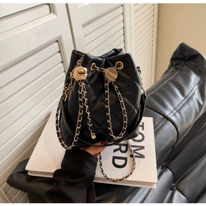Detail of quilted leather bucket bag with gold chain strap and drawstring closure
