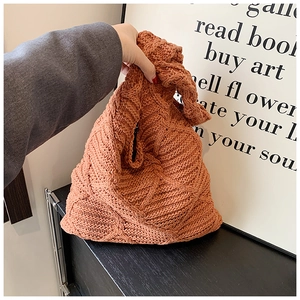 Dettaglio borsa tote in maglia arancione portata a mano con trama intrecciata a rombi