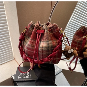 Vue détaillée du sac seau à carreaux rouges avec poignée en cuir et breloque en peluche