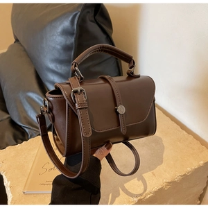 Detail of dark brown vintage crossbody bag with matte leather finish and metal clasp
