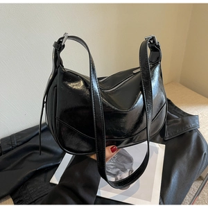 Detail of a retro black wax leather crescent bag with silver zipper on a leather jacket