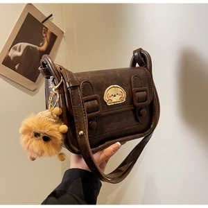 Détail d'un sac à bandoulière marron rétro avec broderie chien et pompon jaune vif