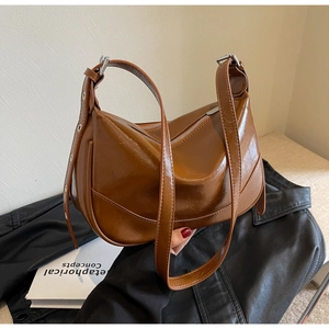 Close-up of caramel brown glossy leather bag with adjustable silver buckle and zipper