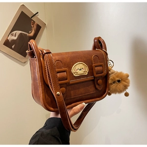 Vue détaillée du sac bandoulière marron rétro avec broderie chiot et breloque peluche
