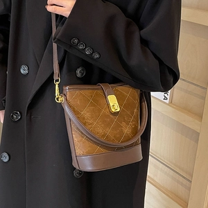 Brown quilted bucket bag with white stitching and gold hardware on model