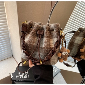 Détail du sac seau en peluche à carreaux avec poignée tressée et breloque monstre