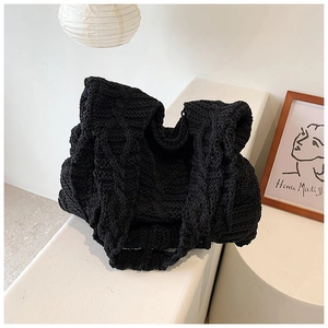 Macro di una borsa tote nera in maglia grossa con trama a trecce su un davanzale bianco