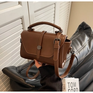 Detail of dark brown vintage leather crossbody bag featuring a classic buckle closure