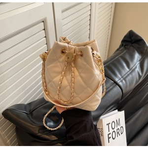 Detail of light beige quilted bucket bag with golden chain strap and sphere lock