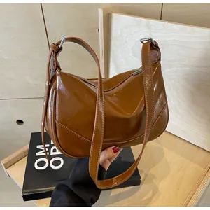 Close-up of brown oiled leather shoulder bag with adjustable strap and silver buckle