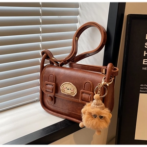 Détail d'un sac à bandoulière vintage marron avec écusson chien et pompon en fourrure