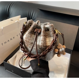 Détail du sac seau en laine à carreaux avec poignée en cuir dans un coffret cadeau