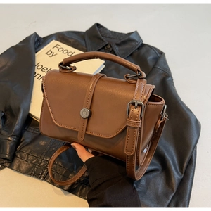 Detailed close-up of dark brown leather crossbody bag with vintage gunmetal buckle hardware