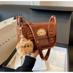 Détail du sac à bandoulière vintage marron avec broderie chien et charm pompon en fourrure
