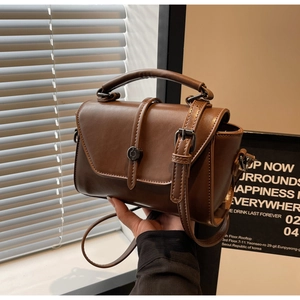 Detail of vintage brown leather handbag with metallic buckle and slim shoulder strap