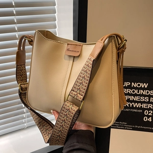 Chic cream bucket bag with brown leather trim and stylish patterned wide shoulder strap