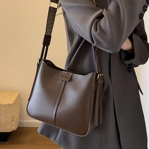 Dark brown leather bucket bag with wide woven strap and embossed logo detail