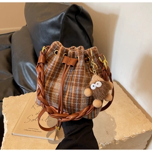 Détail du sac seau à carreaux avec anse en cuir tressé et peluche décorative