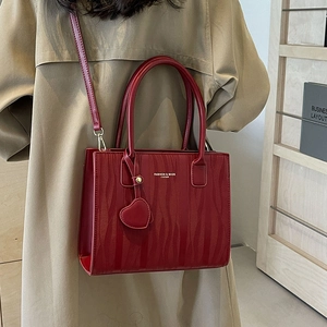 Sac à main de mariage rouge élégant avec texture ondulée et pendentif coeur sur modèle
