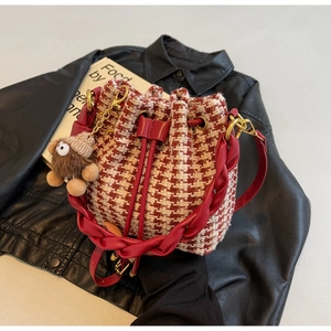 Détail du sac seau à motif pied-de-poule rouge avec cordon en cuir et breloque pelucheuse