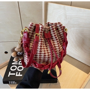 Détail du sac seau à motif pied-de-poule rouge et blanc avec cordon et charm en peluche