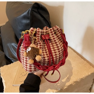 Détail du sac seau à motif pied-de-poule avec poignée tressée et charm peluche