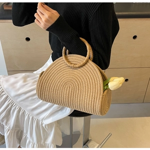 Chic woven straw handbag with circular handles shown in a minimalist lifestyle setting