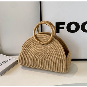 Detailed close-up of a woven straw bucket bag with round handles and a semi-circular texture