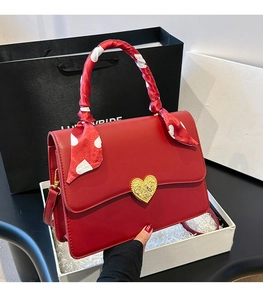Détail du sac de mariage rouge avec fermoir cœur doré et poignée enroulée d'un foulard