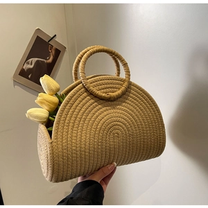 Detail of woven straw tote bag featuring sturdy circular handles and textured patterns